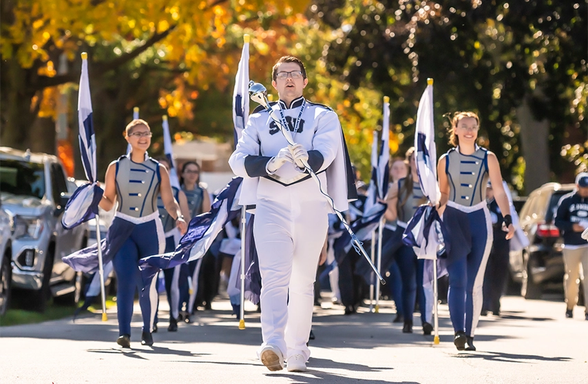 Students marching down the street in a homecoming parade