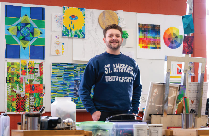 A student standing in an art studio surrounded by art pieces