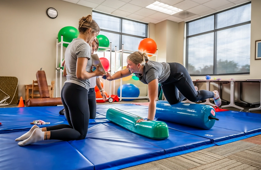 Two students practice motor skills in a physical therapy class.