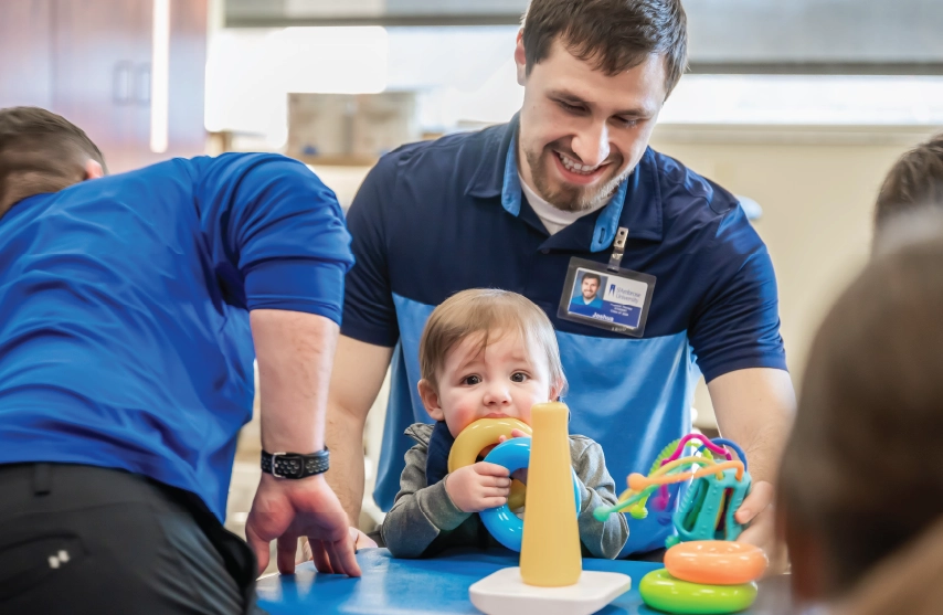 Physical therapist assesses young patient in pediatrics lab.