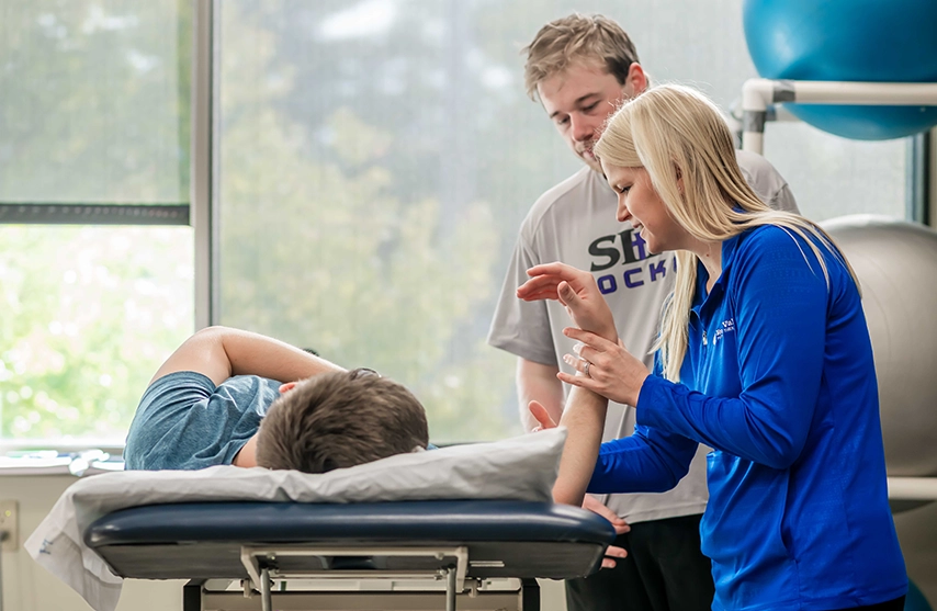 Physical therapy students work with a patient on a treatment table during a rehabilitation session.