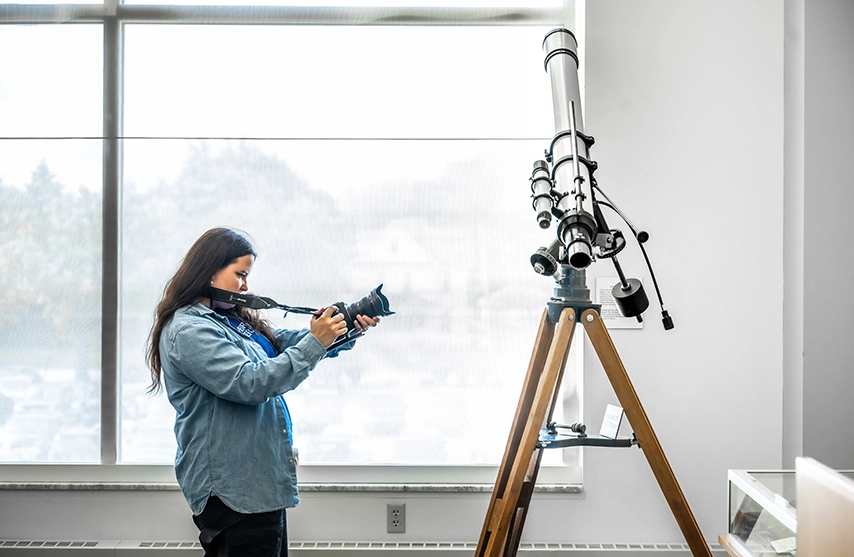 A woman takes a photo of a telescope at Menke Observatory.