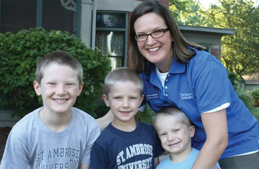 A smiling woman embracing three smiling children.