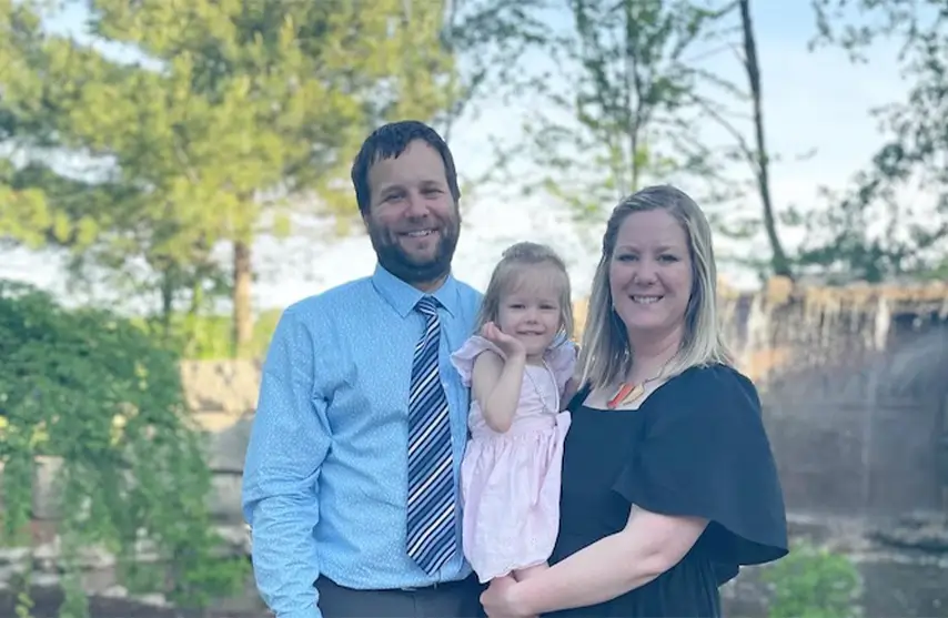 A woman holding her child next to her partner.