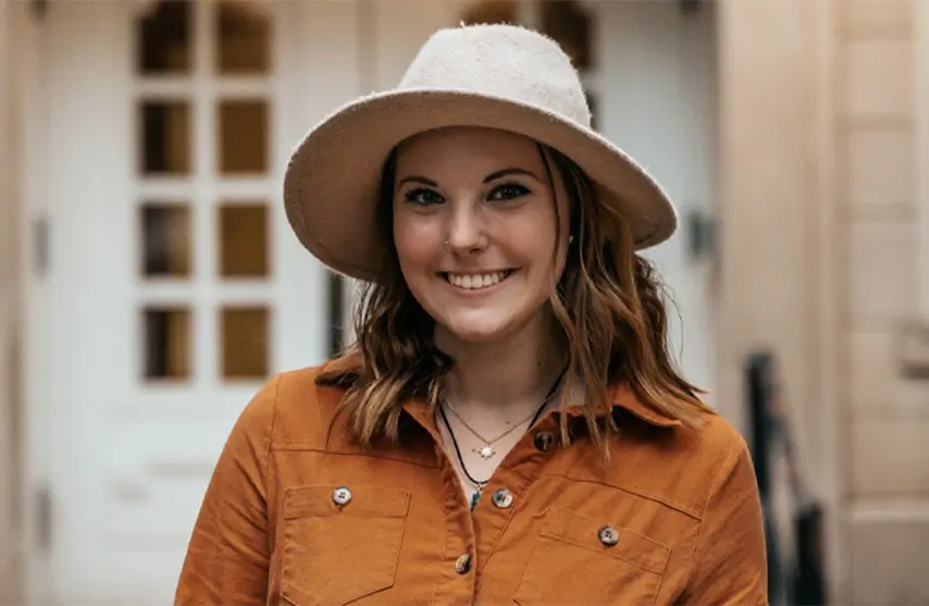Woman in hat smiling outdoors.