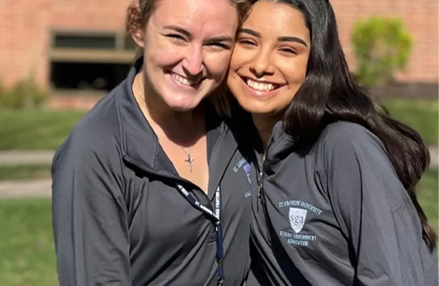 Two female students hugging and posing for a picture.