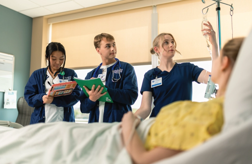 nursing students in navy scrubs attend to patient