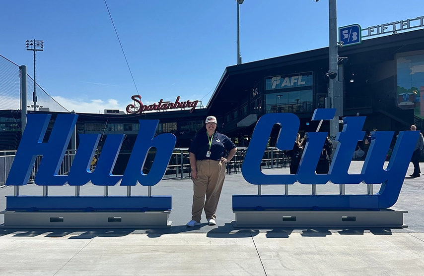 Bailey Conner smiles between two blue signs that read 