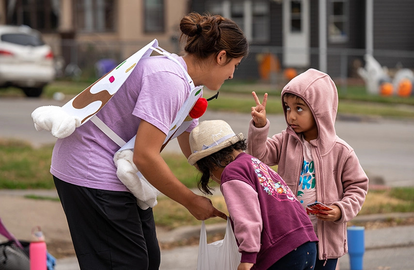 A women's soccer player works with two children in learning soccer.