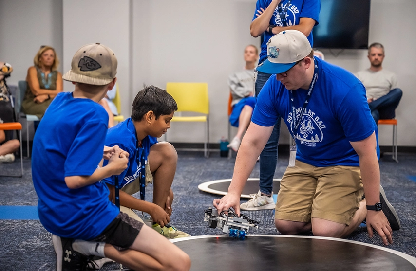 An instructor works with children during the coding summer camp.