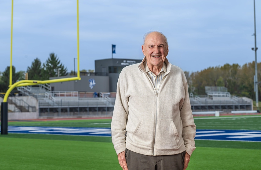 Donor Ivan Schrodt poses outside in front of the Jack and Pat Bush Stadium, home of the St. Ambrose Fighting Bees.