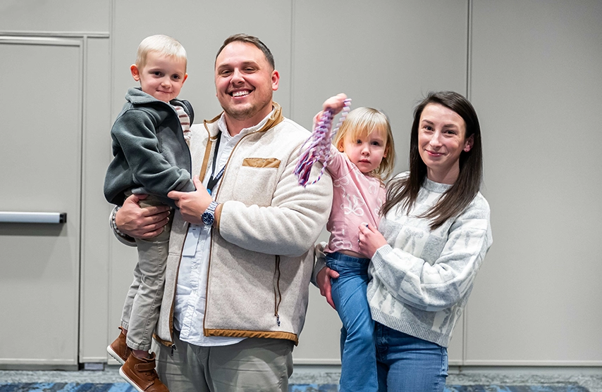 Kara DeBaker, her husband, and two kids smile at the camera.