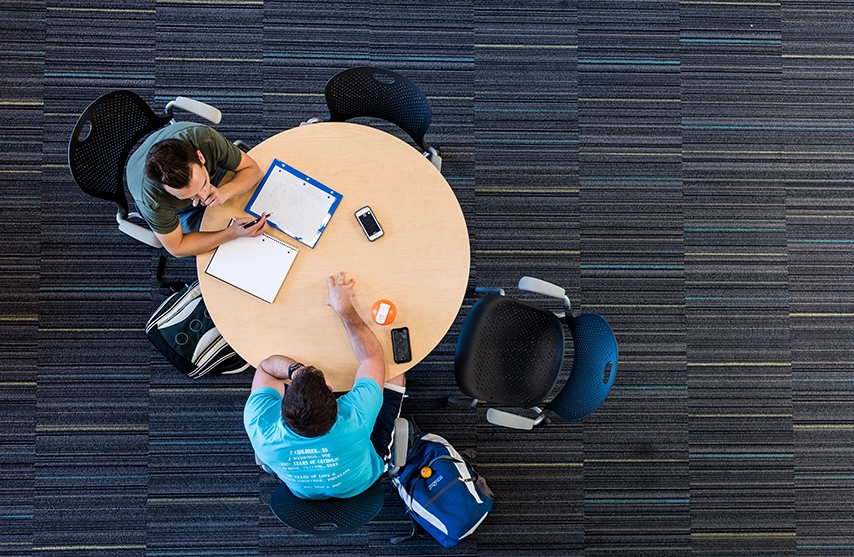 Two students at St. Ambrose University sit around a table and study.