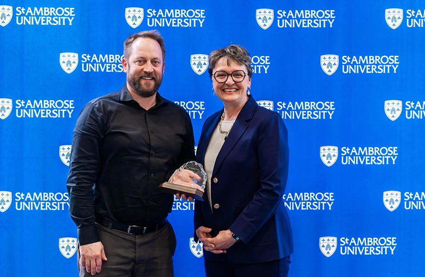 Whalen Fitzgibbon Award winner, Nick Enz, smiles into the camera as he stands next to St. Ambrose University President Amy C. Novak, EdD.
