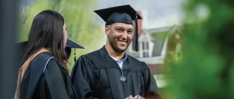 Graduate on stage smiling in cap and gown.