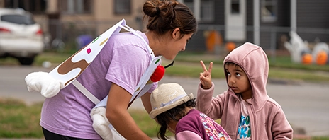 A women's soccer player works with two children in learning soccer.