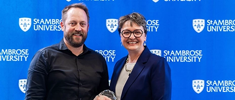 Whalen Fitzgibbon Award winner, Nick Enz, smiles into the camera as he stands next to St. Ambrose University President Amy C. Novak, EdD.
