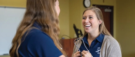 A woman conducting an evaluation on another woman during a physical therapy training.