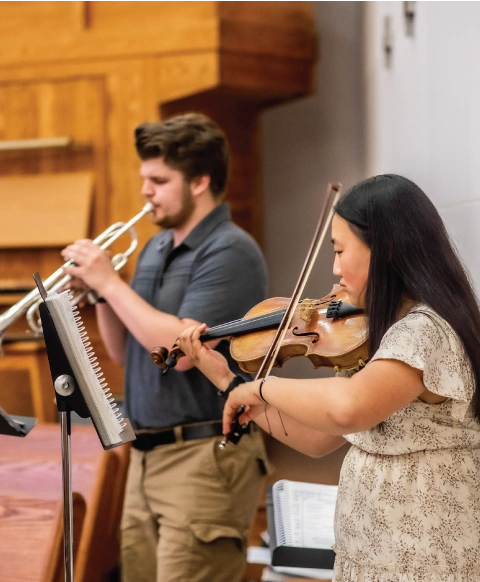 A man playing the trumpet and a woman playing the violin.