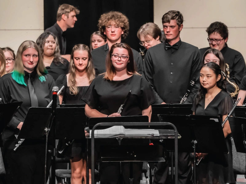 Members of the Symphonic Band stand together at a concert.