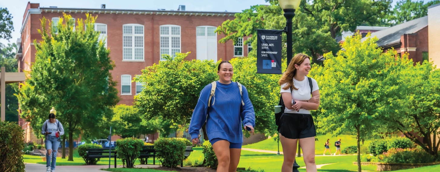 Two students walking across campus, smiling.