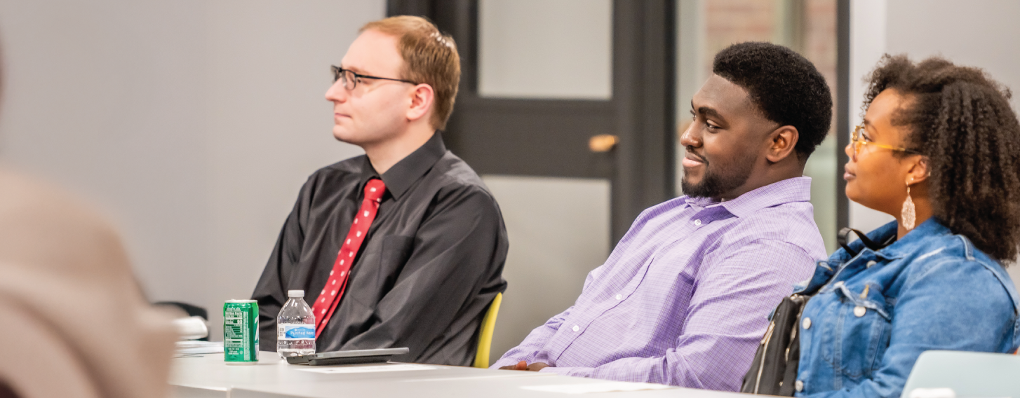 Three students sit at a table during a workforce development class.